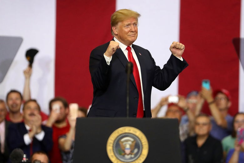 Trump pumps his fists from behind a lectern.